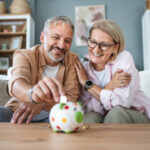 Happy mature couple inserting coins in a piggybank